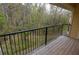 This balcony features a wooden floor, black metal railing, and a wooded view at 8659 Fancy Finch Dr # 202, Tampa, FL 33614
