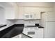 Well-maintained kitchen featuring white appliances and dark countertops at 8659 Fancy Finch Dr # 202, Tampa, FL 33614