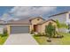 Tan single-Gathering home featuring a two-car garage, neutral landscaping, and a well-manicured lawn at 9313 Channing Hill Dr, Ruskin, FL 33573