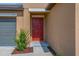 Close-up of a front door featuring a red door, stone accents, and lush landscaping at 9313 Channing Hill Dr, Ruskin, FL 33573