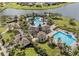 An aerial view showcasing the community pools, clubhouse, and a tranquil lake, surrounded by lush landscaping at 9313 Channing Hill Dr, Ruskin, FL 33573