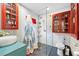 Bright bathroom featuring red cabinets, white tile walls, glass shower door, and stylish sink at 13381 Glory Ln, Brooksville, FL 34614