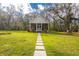 Inviting cottage-style home with a stone path leading to the screened porch in a serene setting at 13381 Glory Ln, Brooksville, FL 34614