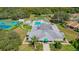 Aerial view of community clubhouse, pool, and tennis courts surrounded by mature trees at 13422 Niti Dr, Hudson, FL 34669