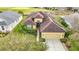 Aerial view of a tan home with a brown roof, solar panels, and well-manicured landscaping at 13422 Niti Dr, Hudson, FL 34669