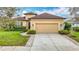 Inviting tan home featuring a spacious driveway leading to an attached two-car garage and lush landscaping at 13422 Niti Dr, Hudson, FL 34669