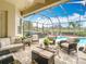 Screened-in lanai with comfortable seating area and a view of the pool and golf course at 13422 Niti Dr, Hudson, FL 34669