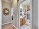 View of a bathroom with a white toilet, vanity, and shower with blue accents from a hallway at 13454 Graham Yarden Dr, Riverview, FL 33579
