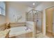 Relaxing main bathroom featuring a soaking tub, glass-enclosed shower, and neutral tile finishes at 13454 Graham Yarden Dr, Riverview, FL 33579