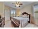 Well-lit main bedroom with a decorative ceiling fan, windows, and a comfortable bed at 13454 Graham Yarden Dr, Riverview, FL 33579