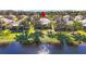 Waterfront home showcasing lush green lawn, mature trees, and tranquil lake views in the backyard at 16023 Golden Lakes Dr, Wimauma, FL 33598