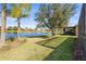 This manicured backyard overlooks a serene lake, featuring lush lawn and mature landscaping at 16023 Golden Lakes Dr, Wimauma, FL 33598