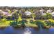 Waterfront home showcasing lush green lawn, mature trees, and tranquil lake views in the backyard at 16023 Golden Lakes Dr, Wimauma, FL 33598