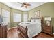 Bedroom featuring a wooden bed frame, hardwood floors, bedside tables, and soft, natural light at 16023 Golden Lakes Dr, Wimauma, FL 33598