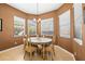 Dining room showcases a round table, four chairs, chandelier, and three sunlit windows with blinds at 16023 Golden Lakes Dr, Wimauma, FL 33598