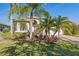 Charming home exterior with lush landscaping, palm trees, and a well-manicured lawn at 16023 Golden Lakes Dr, Wimauma, FL 33598