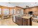 Kitchen island boasts a stainless steel sink, granite countertops, wooden cabinets, and tile flooring at 16023 Golden Lakes Dr, Wimauma, FL 33598