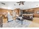Open-concept living room flows into the kitchen featuring a leather couch, ceiling fan, and large area rug at 16023 Golden Lakes Dr, Wimauma, FL 33598