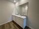 Bathroom featuring a dual sink vanity, a large mirror and shower with wood look flooring at 17048 James Trl, Parrish, FL 34219