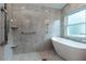 Luxurious bathroom featuring a soaking tub, marble-style tiling, and a walk-in shower at 17508 Isbell Ln, Odessa, FL 33556