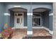 Covered front porch showcasing brick flooring, columns, decorative accents and charming front door at 17508 Isbell Ln, Odessa, FL 33556