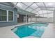 A beautiful blue swimming pool with a screened enclosure and covered patio in the background at 17508 Isbell Ln, Odessa, FL 33556