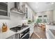Well-equipped kitchen with gas range, stylish hood, white cabinets, and open dining area at 2630 Yellow Sundial Loop, Ruskin, FL 33570