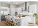 Bright, all-white kitchen featuring an island with seating, stainless steel appliances, and tile backsplash at 2630 Yellow Sundial Loop, Ruskin, FL 33570