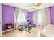 Bright bedroom with purple walls, tile floors, ceiling fan, and exercise equipment at 2710 Hibiscus W Dr, Belleair Beach, FL 33786