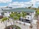Beautiful two-story home with a green roof, white exterior, and lush tropical landscaping with palms at 2710 Hibiscus W Dr, Belleair Beach, FL 33786