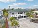 Eye-catching two-story home with a green roof, a white exterior, and beautiful landscaping with palms at 2710 Hibiscus W Dr, Belleair Beach, FL 33786