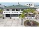 Elegant two-story home featuring a green roof, white exterior and beautiful landscaping with mature palms at 2710 Hibiscus W Dr, Belleair Beach, FL 33786