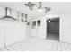 Bright kitchen featuring white tile floors and backsplash, stainless steel hood, and stylish lighting at 2710 Hibiscus W Dr, Belleair Beach, FL 33786