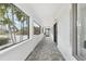 Covered walkway features tile flooring, large windows overlooking lush landscaping, and white brick walls at 2710 Hibiscus W Dr, Belleair Beach, FL 33786