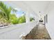 Long, brick-floored porch with white brick walls, columns, and lush tropical views at 2710 Hibiscus W Dr, Belleair Beach, FL 33786