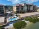 Community pool and complex aerial view with lush landscaping along a bay and beach access at 5301 Gulf Blvd # C202, St Pete Beach, FL 33706