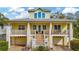Charming yellow two-story home with a welcoming front porch, brick stairs, and well-manicured landscaping at 536 Ontario Ave, Crystal Beach, FL 34681
