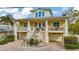 Inviting two-story yellow home featuring a charming brick driveway, decorative columns, and a covered porch at 536 Ontario Ave, Crystal Beach, FL 34681