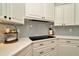 Corner view of a modern kitchen with a cooktop, countertops, and blue herringbone backsplash at 536 Ontario Ave, Crystal Beach, FL 34681