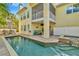 Exterior shot of a charming yellow home with a luxurious pool and spa with covered patio and balcony at 536 Ontario Ave, Crystal Beach, FL 34681