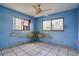 Empty bedroom with blue walls, two windows, ceiling fan and white tile flooring at 5698 26Th N Ave, St Petersburg, FL 33710