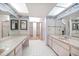 Bathroom with a double sink vanity, patterned wallpaper, and walk-in closet access at 700 Island Way # 404, Clearwater Beach, FL 33767