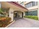 Covered condo entrance featuring brick pavers, stone accents, and manicured landscaping at 700 Island Way # 404, Clearwater Beach, FL 33767