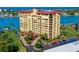A waterfront condo building with tropical landscaping, a parking lot, and beautiful ocean views at 700 Island Way # 404, Clearwater Beach, FL 33767