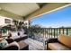 Relax on your balcony! Cozy seating area on a covered balcony with iron railings and views of the street and water at 74 Gulf Blvd # 2B, Indian Rocks Beach, FL 33785