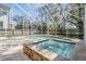 This screen enclosed pool area has a spa and pool surrounded by travertine pavers at 102 Adriatic Ave, Tampa, FL 33606