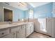 Bathroom with a large mirror, double sink vanity, walk-in bathtub, and blue walls at 10237 Collar Dr, San Antonio, FL 33576