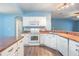 Galley style kitchen featuring white appliances and wood floors, seamlessly connected to other living spaces at 10237 Collar Dr, San Antonio, FL 33576