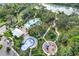 Aerial view of the community with pools, splash pad, playground, and walking trails nestled among lush greenery at 10432 High Noon Trl, Parrish, FL 34219
