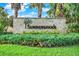 Summerwoods community entrance sign amidst lush landscaping, framed by palm trees and vibrant greenery at 10432 High Noon Trl, Parrish, FL 34219